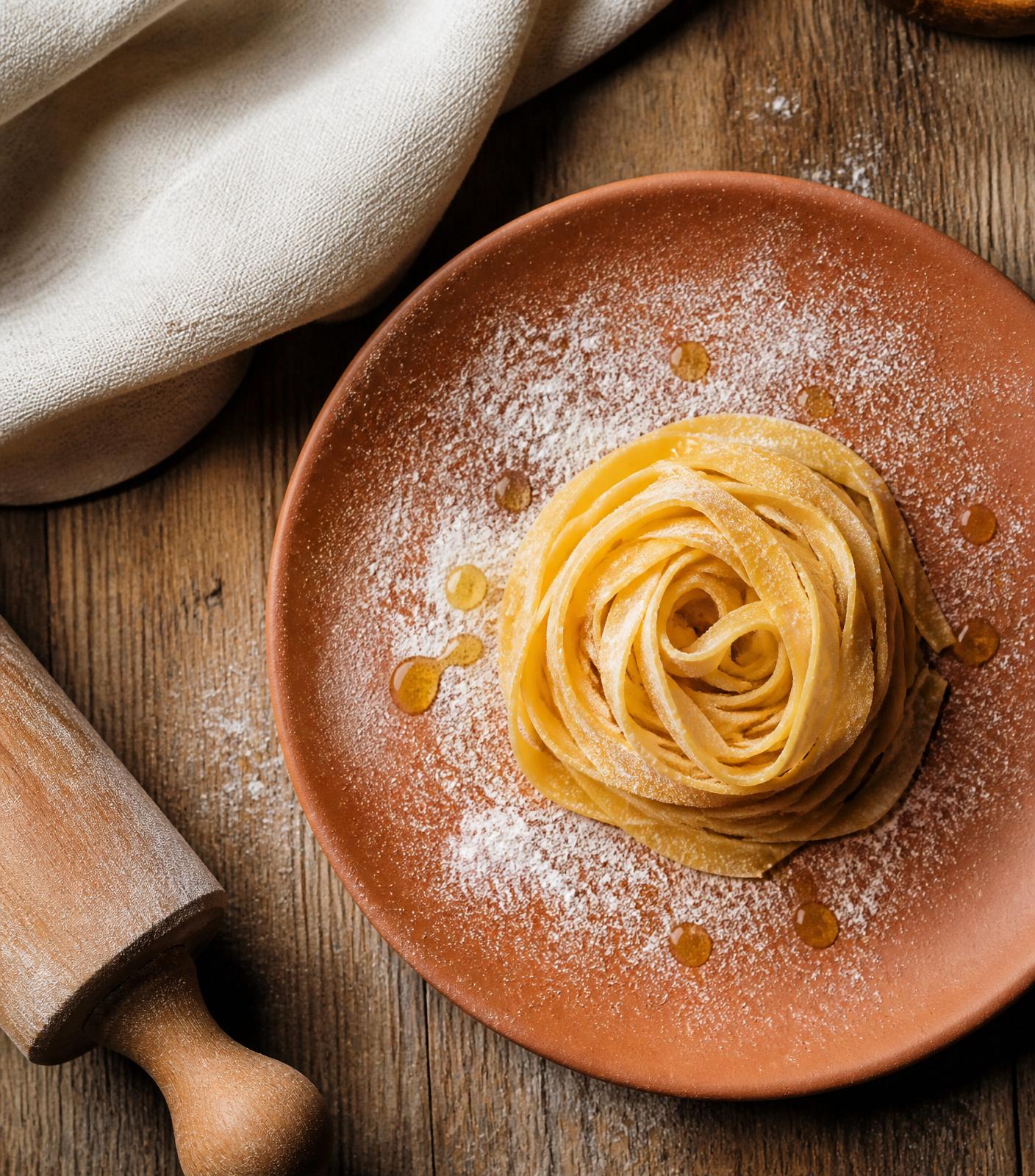 Tagliatelle fresche fatte a mano su piatto terracotta